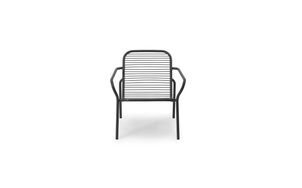En moderne metalstol med en række vandrette lameller på sæde og ryglæn, med armlæn og fire ben, afbilledet mod en almindelig hvid baggrund. Normann Copenhagen - Vig Loungestol.