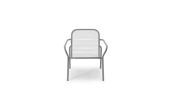 En moderne NORMANN COPENHAGEN - Vig Loungestol med et minimalistisk design, med vandrette lameller på sæde og ryglæn og slanke, buede armlæn. stolen præsenteres mod en almindelig hvid baggrund.