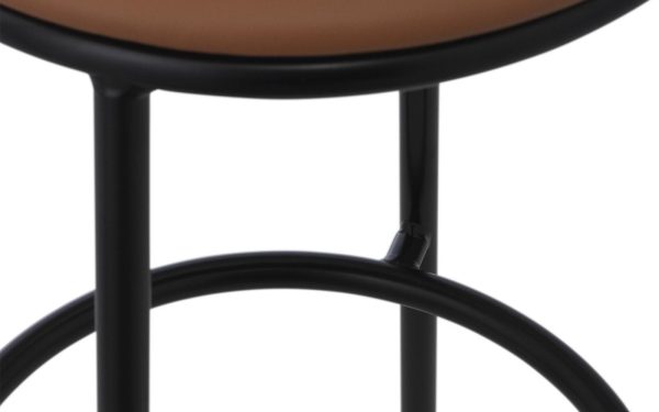 Nærbillede af en sort metalstol med et rundt, brunt sæde. Billedet fokuserer på leddet, hvor et af benene møder sædets støttering, hvilket viser dets elegante design.