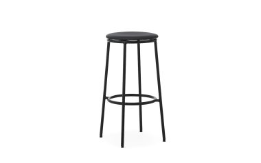 En sort barstol med et rundt polstret sæde og slanke metalben, med en cirkulær fodstøtte fra TomorrowsDesign, isoleret på en hvid baggrund.
