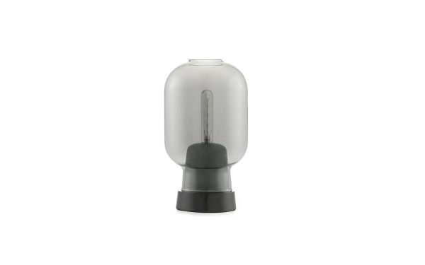 Et isoleret billede af en Normann Copenhagen - Amp Bordlampe med sort gummi- og plastikfod, vist mod en almindelig hvid baggrund.