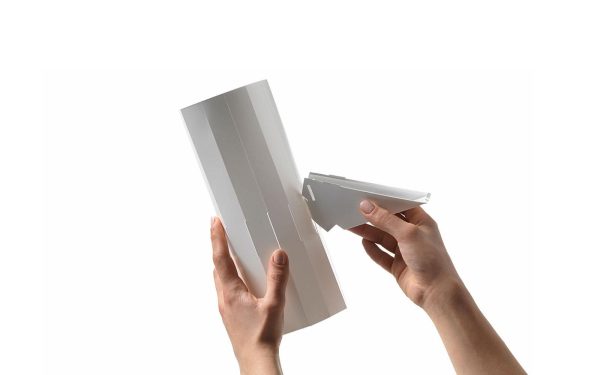To hænder holder og samler stykker af en NORMANN COPENHAGEN - Norm 69 Lampe Lille model på hvid baggrund.