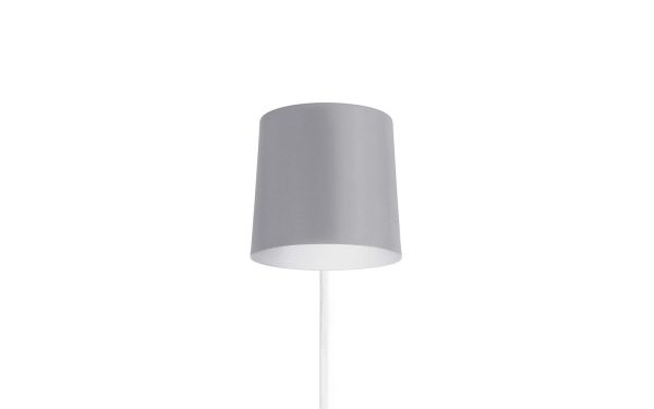 En enkel, moderne NORMANN COPENHAGEN - Rise Væglampe med en hvid cylindrisk skærm og en slank stilk, sat mod en almindelig hvid baggrund.