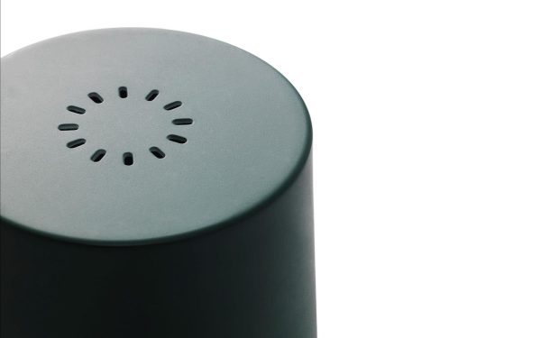 Et nærbillede af NORMANN COPENHAGEN - Rise Væglampe, en moderne, cylindrisk enhed med et højttalergitter på toppen, vist mod en hvid baggrund.