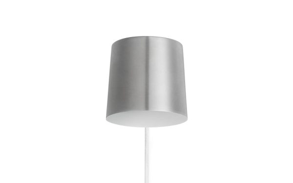 En minimalistisk moderne designlampe med en cylindrisk sølvskærm og en hvid base, isoleret på en hvid baggrund.