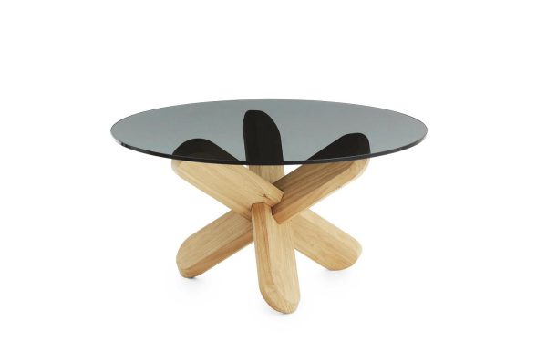 Et moderne sofabord med en rund glasplade og en træbund formet som et x, sat mod en almindelig hvid baggrund, der viser TomorrowsDesign-etos.