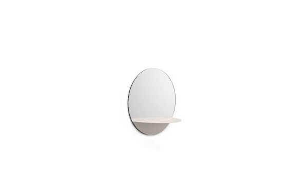 Et ovalt spejl med en lille, afrundet hylde, fastgjort til en almindelig hvid væg. designet er minimalistisk og moderne NORMANN COPENHAGEN Horizon Spejl.