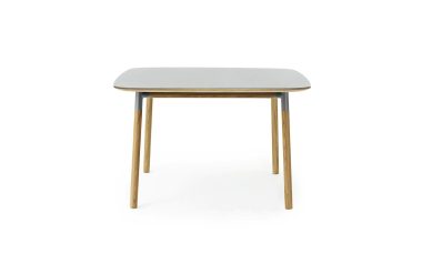 Et moderne bord med en rektangulær, grå bordplade og fire træben, isoleret på en hvid baggrund. Designet er enkelt og moderne.
