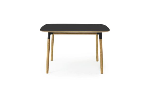 Et moderne, minimalistisk bord med en rektangulær sort plade og fire vinklede træben, isoleret på en hvid baggrund, perfekt til moderne interiørrum.