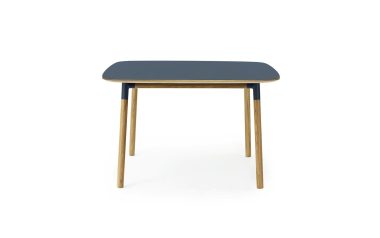Et moderne bord med en marineblå rektangulær plade og fire ben i naturligt træ, designet af TomorrowsDesign, isoleret på en hvid baggrund.