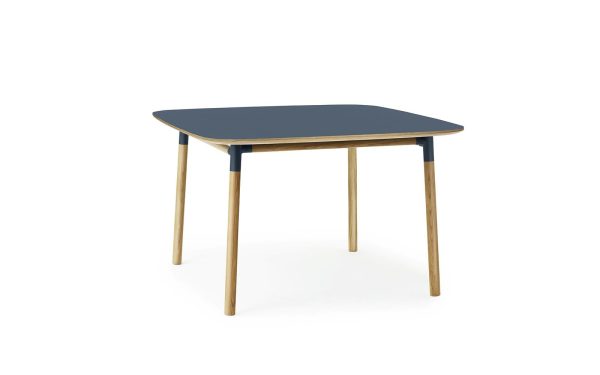Et minimalistisk firkantet bord med en mørkeblå plade og ben i naturligt træ, der viser moderne design, sat mod en hvid baggrund.