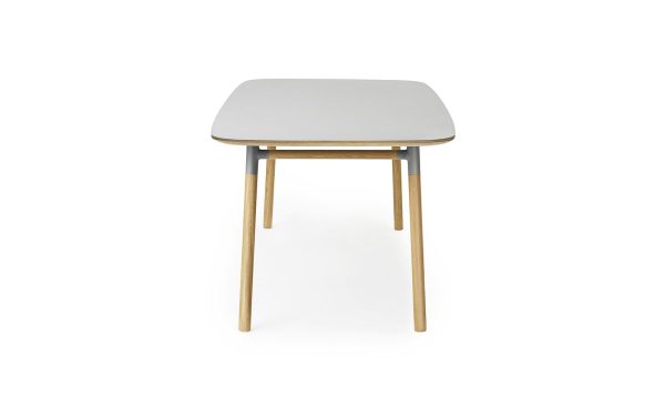 En moderne firkantet skammel med en lysegrå top og træben, sat mod en almindelig hvid baggrund, er indbegrebet af minimalistisk design.