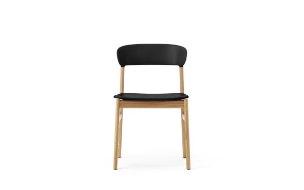 En moderne stol med sort sæde og ryglæn, understøttet af lyse træben, står isoleret mod en almindelig hvid baggrund. Dette stykke viser eksemplarisk NORMANN COPENHAGEN - Herit Spisebordsstol-æstetik.