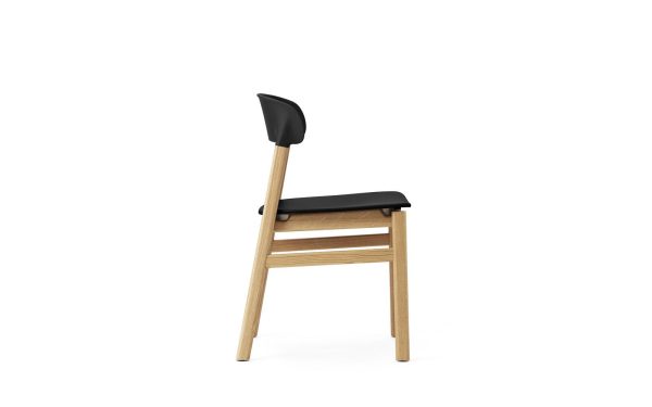 En moderne NORMANN COPENHAGEN - Herit Spisebordsstol med sort sæde og ryglæn samt lyse træben. stolen vises på en almindelig hvid baggrund.