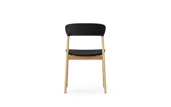 En moderne stol med sort ryglæn, lyse træben og stel og et vævet sæde, isoleret på hvid baggrund. Normann Copenhagen - Herit Spisebordsstol