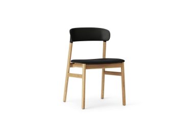 EN NORMANN COPENHAGEN - Herit Spisebordsstol med en lys træramme og sort polstret sæde og ryglæn, isoleret på en hvid baggrund.
