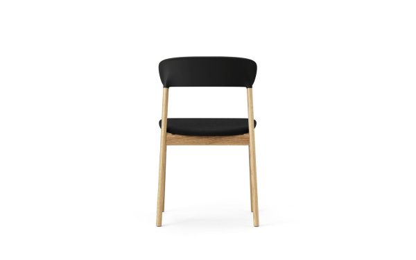 EN NORMANN COPENHAGEN - Herit Spisebordsstol med sort sæde og ryglæn, sat på en ramme af naturligt træ med fire ben, vist mod en almindelig hvid baggrund.
