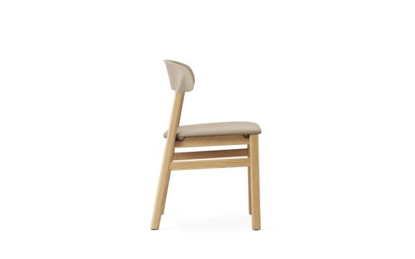 En moderne designstol med en beige sædepude og ryglæn, parret med en let træramme og -ben, isoleret på en hvid baggrund.