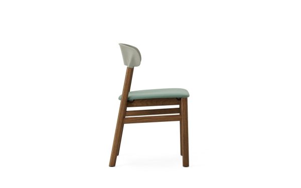 En enkel stol med træstel og blågrønt polstret sæde, set fra en lille vinkel, der viser ryggen og den ene side, mod en almindelig hvid baggrund. Dette stykke passer problemfrit ind i moderne interiørdesign.