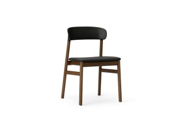 En moderne stol med stel i valnød og sort polstret sæde og ryglæn, isoleret på en hvid baggrund, eksemplificerer skandinavisk designmøbler.