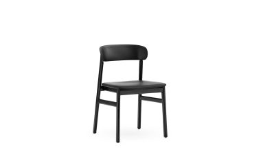 En enkel sort stol med buet ryglæn og fire ben, designet af TomorrowsDesign, placeret mod en almindelig hvid baggrund.