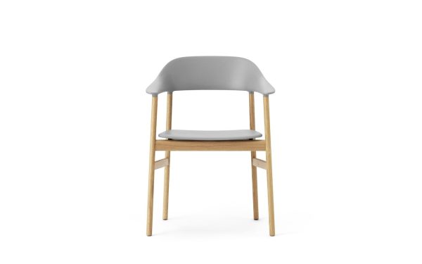 En moderne NORMANN COPENHAGEN - Herit Spisebordsstol med et gråt plastikryglæn og sædehynde på en træramme, isoleret på en hvid baggrund.