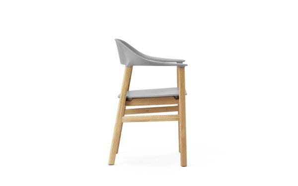 En moderne barstol med gråt plastiksæde og træben, vist i en enkel, isoleret hvid baggrund. NORMANN COPENHAGEN - Herit Spisebordsstol har et slankt design med lavt ryglæn.