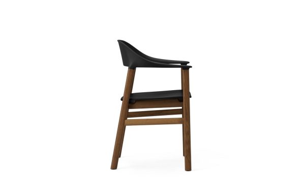 En moderne barstol med sort sæde og træben, isoleret på en hvid baggrund. Skamlen har et minimalistisk interiørdesign med let buet ryglæn og vandret fodstøtte.