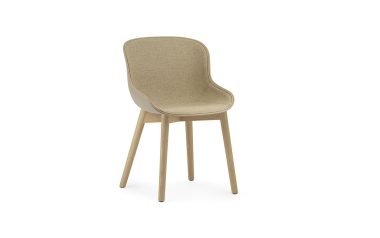 En moderne NORMANN COPENHAGEN - Hyg Spisebordsstol med beige polstring og lyse træben, isoleret mod en hvid baggrund.