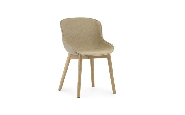 En moderne NORMANN COPENHAGEN - Hyg Spisebordsstol med beige polstring og lyse træben, isoleret mod en hvid baggrund.