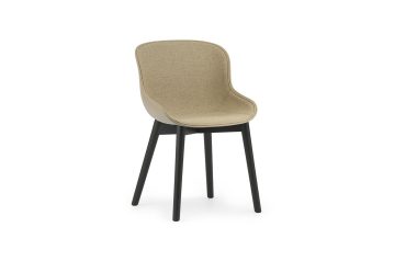 En moderne spisestuestol med beige polstret sæde og ryglæn, kontrasteret af fire sorte tilspidsede ben. Stolen, der viser moderne møbler design, er sat mod en almindelig hvid baggrund.