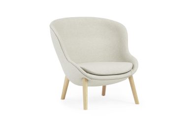 En beige moderne lænestol med glat, buet ryglæn og et polstret sæde, understøttet af fire lyse træben, isoleret mod en hvid baggrund. Perfekt til at forbedre dit interiørdesign.