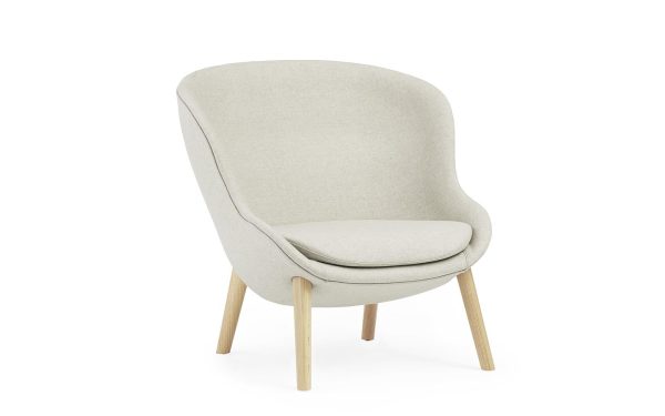 En beige moderne lænestol med glat, buet ryglæn og et polstret sæde, understøttet af fire lyse træben, isoleret mod en hvid baggrund. Perfekt til at forbedre dit interiørdesign.