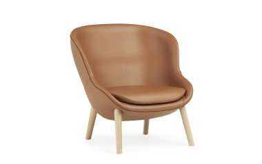 Et moderne NORMANN COPENHAGEN - Hyg Lænestol Low med glat, buet ryglæn og sæde på lyse træben, isoleret mod en almindelig hvid baggrund.