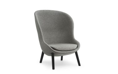 En moderne grå polstret lænestol med højt, buet ryglæn og fire sorte træben, designet til moderne interiør, isoleret på hvid baggrund.