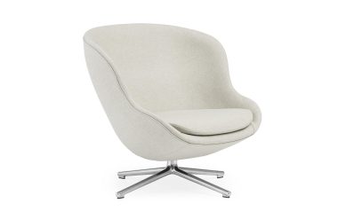 En moderne lysegrå lænestol i stof med høj ryg og bevinget design, med et polstret sæde og en krom stjerneformet base, isoleret på en hvid baggrund. Dette stykke er et eksempel på TomorrowsDesign.
