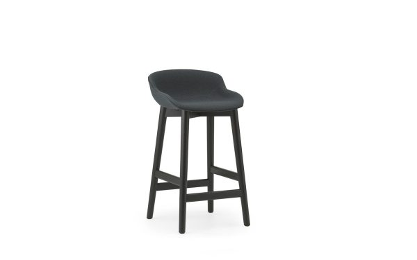 En moderne NORMANN COPENHAGEN - Hyg Barstol 65 med et mørkegrå polstret sæde og sorte træben, isoleret på en hvid baggrund.