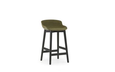 En moderne design barstol med et mørkt træstel og et plys olivengrønt sæde, placeret mod en almindelig hvid baggrund.