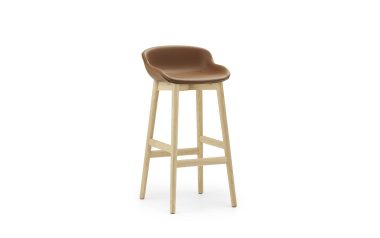 En barstol i moderne design med en lys træramme og et solbrunt lædersæde, isoleret på en hvid baggrund.