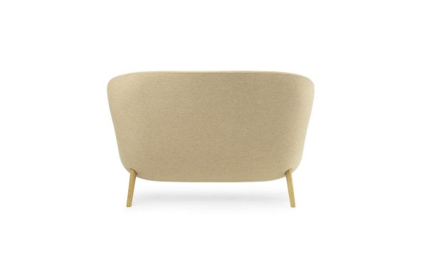En minimalistisk beige NORMANN COPENHAGEN - Hyg Sofa med en glat stoffinish og vinklede træben, vist mod en almindelig hvid baggrund.