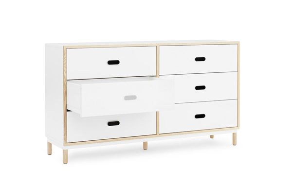 En moderne hvid kommode med seks skuffer, med sorte trækhåndtag og træben, sat mod en almindelig hvid baggrund. Den ene skuffe er delvist åben. Dette stykke er fra TomorrowsDesign-kollektionen.