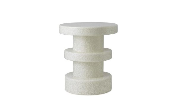 En hvid, cylindrisk tre-lags NORMANN COPENHAGEN - Bit Skammel Stack isoleret på en hvid baggrund. hvert lag har en overflade med ru tekstur, og lagene varierer lidt i diameter.