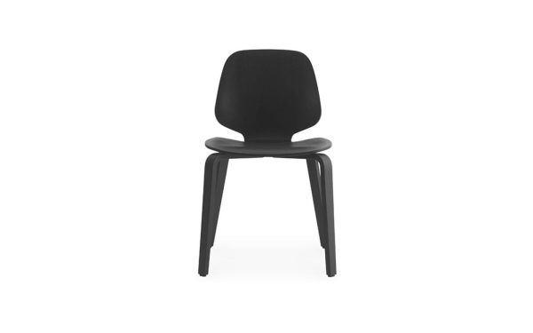 En enkel sort stol med afrundet ryg og sæde, placeret mod en skarp hvid baggrund. Stolen har fire slanke ben og et minimalistisk design.