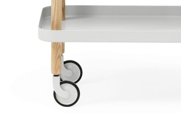 Nærbillede af et NORMANN COPENHAGEN - Rullebord med hvid bakke, træben og slanke hjul til mobilitet.