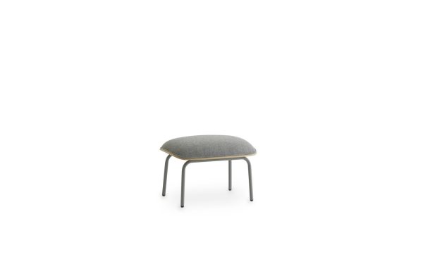 EN NORMANN COPENHAGEN - Pad Fodskammel med en grå pude og slanke, sorte metalben, placeret i midten af en almindelig hvid baggrund.