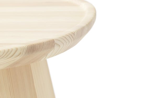 Nærbillede af en NORMANN COPENHAGEN - Pine Sofabord Ø45, med fokus på det runde sæde og en del af benet, der viser træets lagdelte tekstur på en hvid baggrund.
