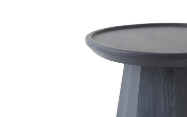Nærbillede af en NORMANN COPENHAGEN - Pine Sofabord Ø45 isoleret mod en hvid baggrund, med fokus på bordpladen og en del af benet.