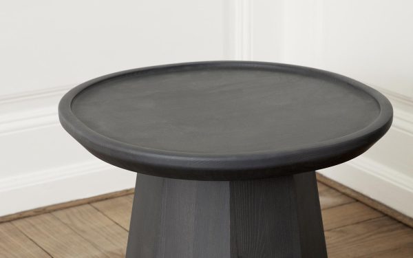 Et sort NORMANN COPENHAGEN - Fyrsofabord Ø45 med rund top, stående på et trægulv mod en hvid væg med hvid fodliste.