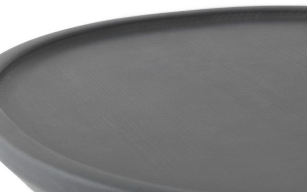 Nærbillede af en NORMANN COPENHAGEN - Pine Sofabord Ø45 med en struktureret overflade, fotograferet mod en lysegrå baggrund. fokus er på bakkens kant, hvilket demonstrerer dets tynde og slanke design.