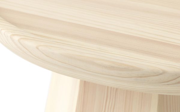 Nærbillede af et NORMANN COPENHAGEN Pine Sofabord Ø65 med fokus på bordpladen og en del af benet, der viser træets naturlige årer og tekstur.